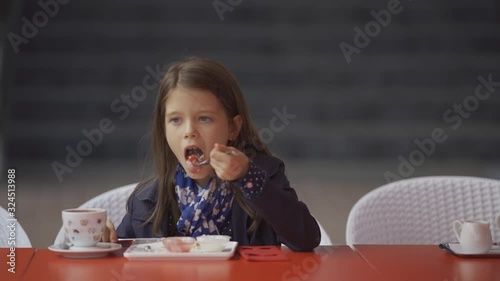  Beautiful little girl has breakfast in a cafe