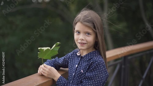 Beautiful little girl with blue eyes in a blue dress on a walk in the park