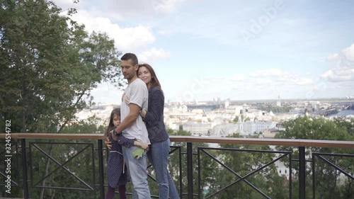 Beautiful young family on a walk, parents with daughter in a park on an alley