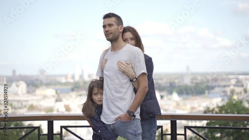 Beautiful young family on a walk, parents with daughter in a park on an alley