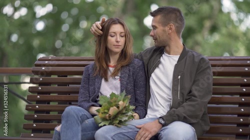 Beautiful couple kisses on a bench in the park, a romantic date