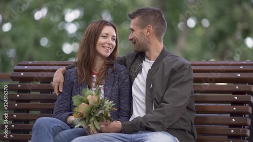 Beautiful couple kisses on a bench in the park, a romantic date