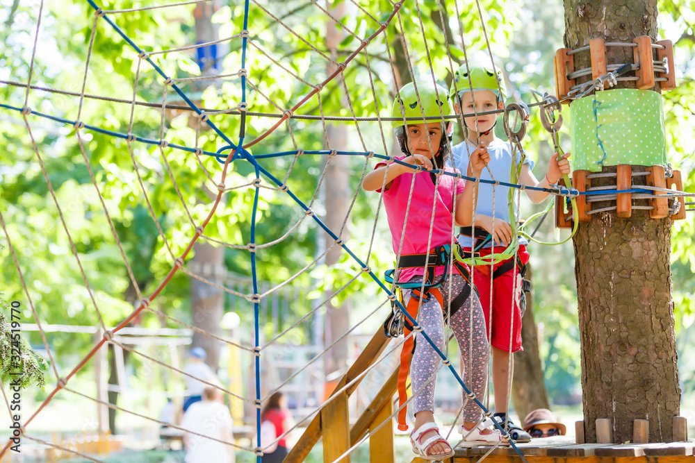 adventure climbing high wire park - children on course rope park in mountain helmet and safety equipment