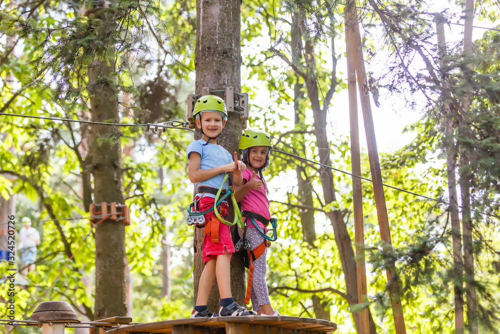 adventure climbing high wire park - children on course rope park in mountain helmet and safety equipment adventure climbing high wire park - children on course rope park in mountain helmet and safety equipment
