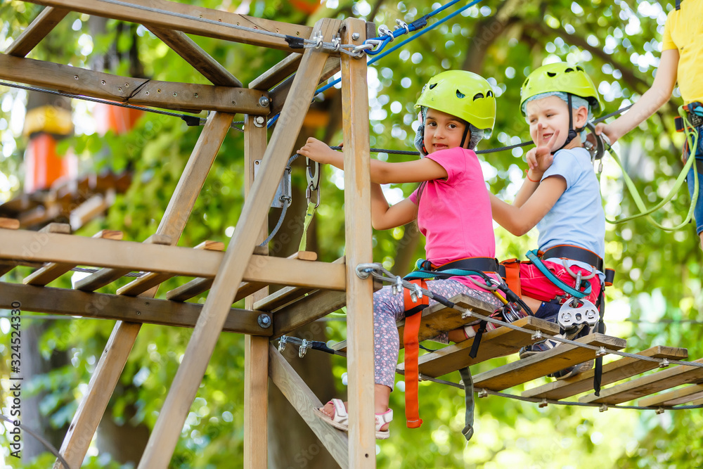 adventure climbing high wire park - children on course rope park in mountain helmet and safety equipment