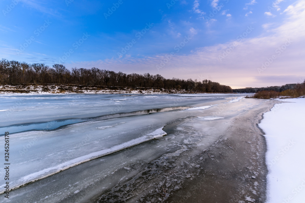 panorama of the winter landscape on the river covered with ice at sunset. pink sky. photo for banner