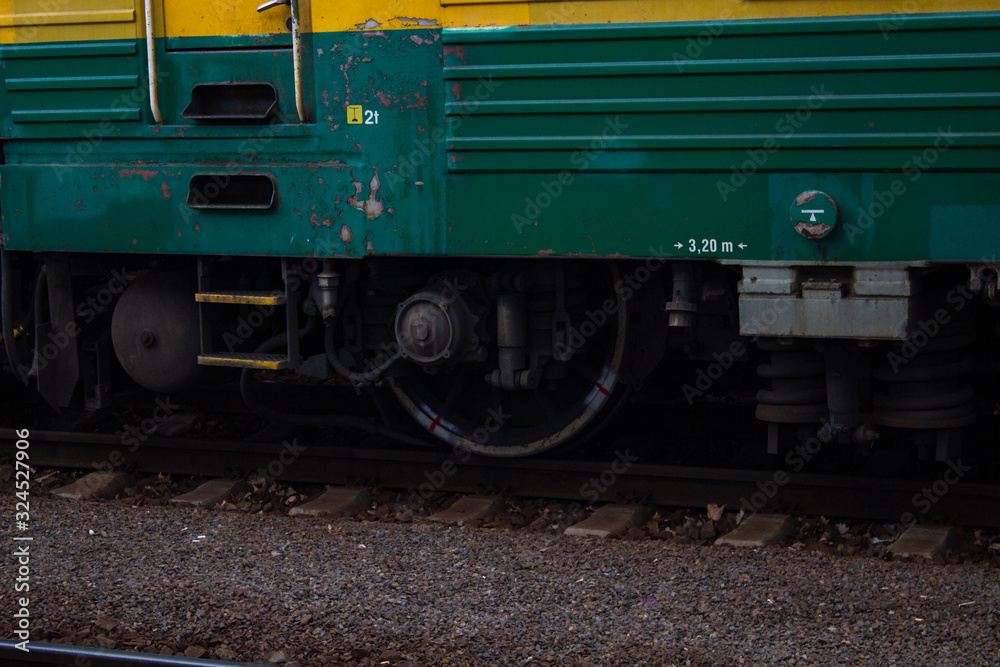 Detail of a green train chassis on rails at a train station