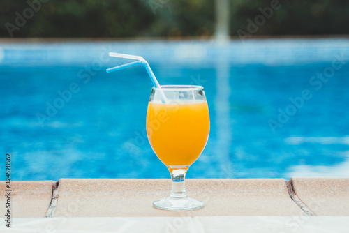 Orange juice near the pool. Space for text.