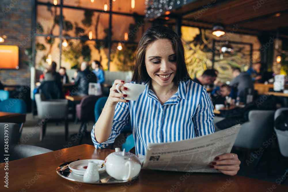 young woman enjoying tea and reading press in cafe bar young woman enjoying tea and reading press in cafe bar