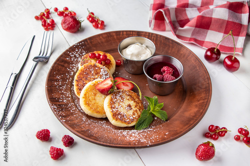 Wallpaper Mural Cottage cheese pancakes, homemade traditional Ukrainian dish syrniki with berry sauce and sour cream on a brown plate on a white background Torontodigital.ca
