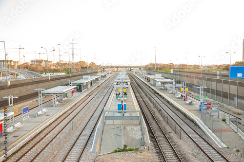 Railroad tracks in the city during daylight hours. There are no trains. People are waiting on the platforms. City Style. Horizontal view.