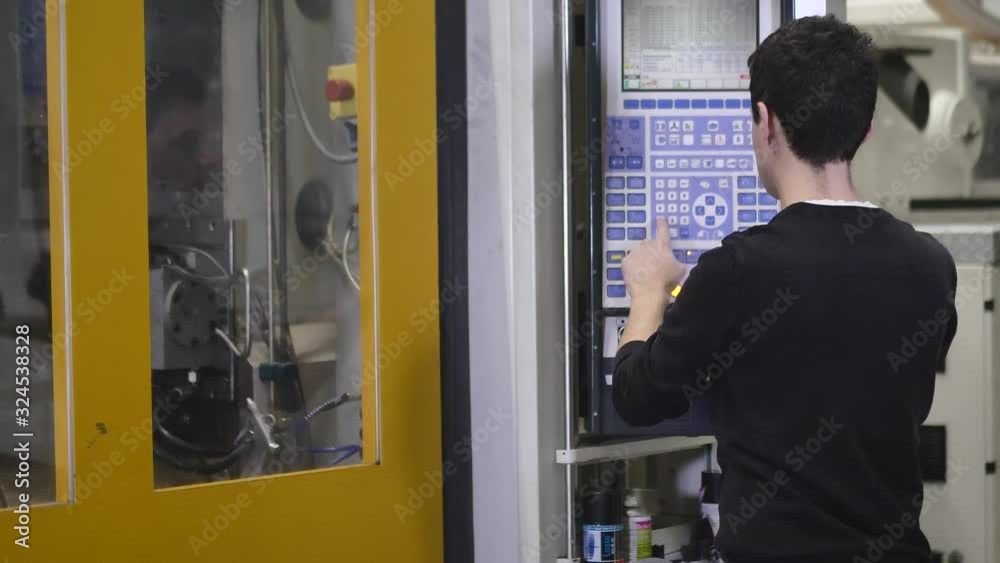 Production Worker Operates the Automatic Injection Molding Machine to Start Production of Molding Housing for the Headlamps in Automotive Factory Production Worker Operates the Automatic Injection Molding Machine to Start Production of Molding Housing for the Headlamps in Automotive Factory