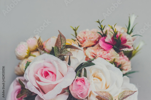 Bouquet of artificial pastel color flowers on gray background  top view with copy space