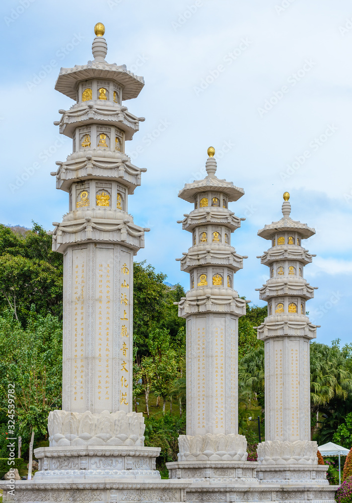 Buddhist stone pillars (prayer flags columns) on the territory of Buddhist center Nanshan on a cloudy day.