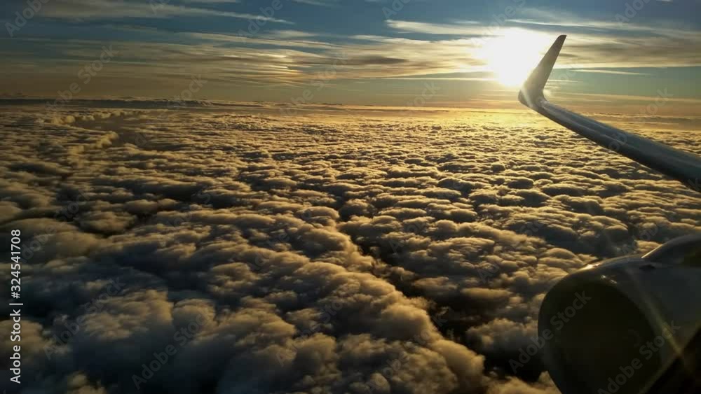 Flying above a layer of Stratus clouds at sunrise with an aircraft's right wing, winglet, and engine visible. Camera locked.
