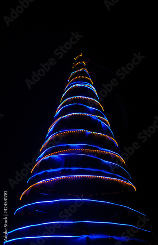 Neon light Christmas tree on a black background with blue and yellow lights