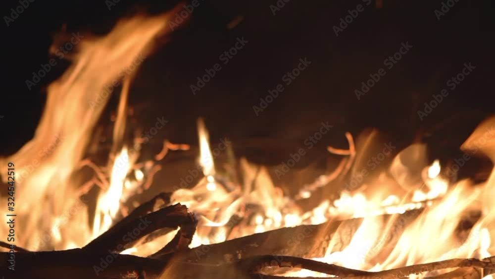 Flames of bonfire and dry burning branches. Close-up of flame, branches and firewood burning and smoldering at dusk. Flames of bonfire and dry burning branches. Close-up of flame, branches and firewood burning and smoldering at dusk.