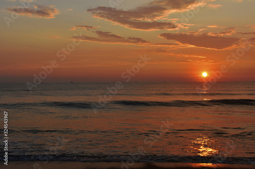 sunset in a ocean with a waves and a beautiful sky in goa beach