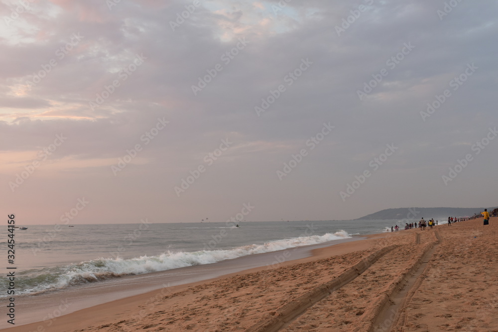 a sand trail of a car in a beach with waves