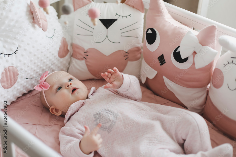 Beautiful baby girl in pink. Cute baby wearing pink body with pink flower headgear. Healthy baby in bed Beautiful baby girl in pink. Cute baby wearing pink body with pink flower headgear. Healthy baby in bed