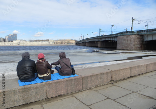 Friends are sitting on the bankment of the river in winter photo