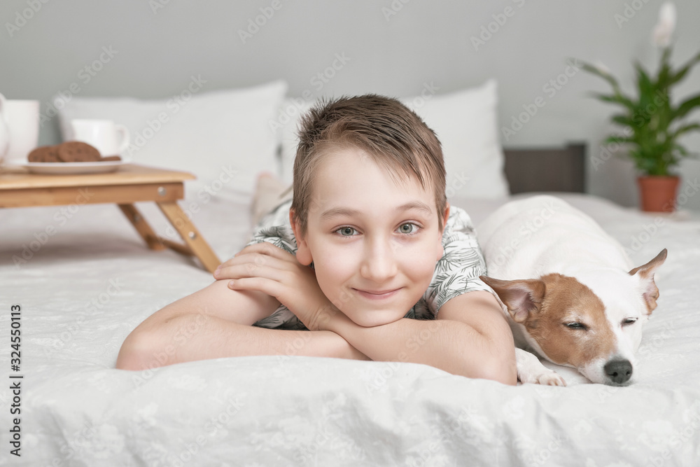 Two friends boy and dog lying together on bed. Boy on bed with dog jack russell terrier. Friendship concept. Cute little boy with funny dog on bed at home. Young Boy Hugging his Dog. Two friends boy and dog lying together on bed. Boy on bed with dog jack russell terrier. Friendship concept. Cute little boy with funny dog on bed at home. Young Boy Hugging his Dog.