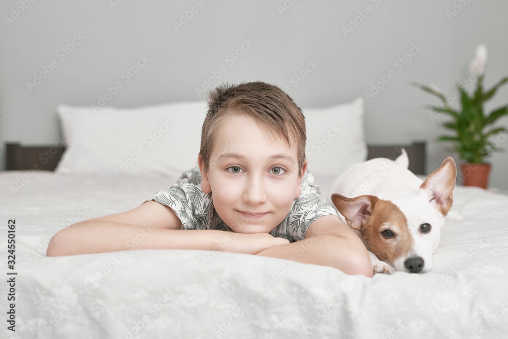 Two friends boy and dog lying together on bed. Boy on bed with dog jack russell terrier. Friendship concept. Cute little boy with funny dog on bed at home. Young Boy Hugging his Dog. Two friends boy and dog lying together on bed. Boy on bed with dog jack russell terrier. Friendship concept. Cute little boy with funny dog on bed at home. Young Boy Hugging his Dog.