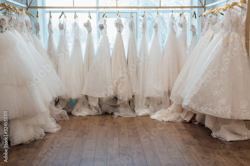 Foto a lot of beautiful white wedding dresses on hangers in the store