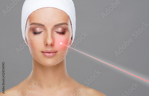 Doctor removing moles using laser ray. Beauty portrait of a young woman. Birt...