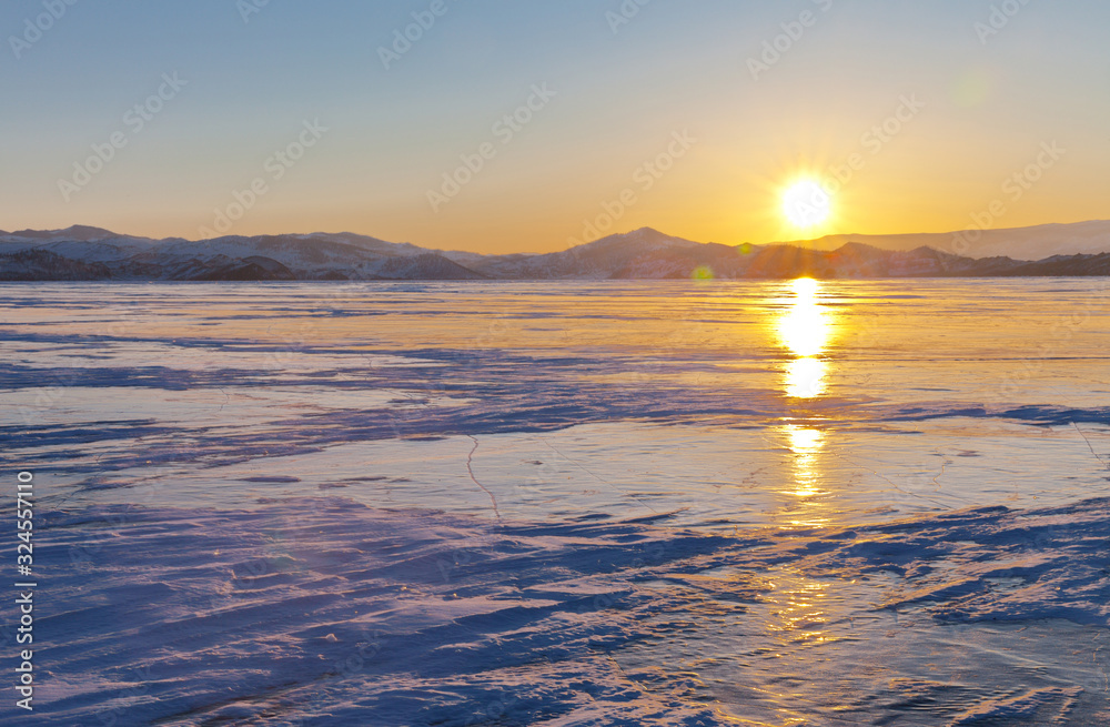 Beautiful winter landscape with the setting sun over the ice-covered Small Sea. Traveling on frozen Lake Baikal. Natural background