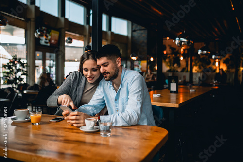 romantic couple in cafeteria drinking coffee and using mobile phone