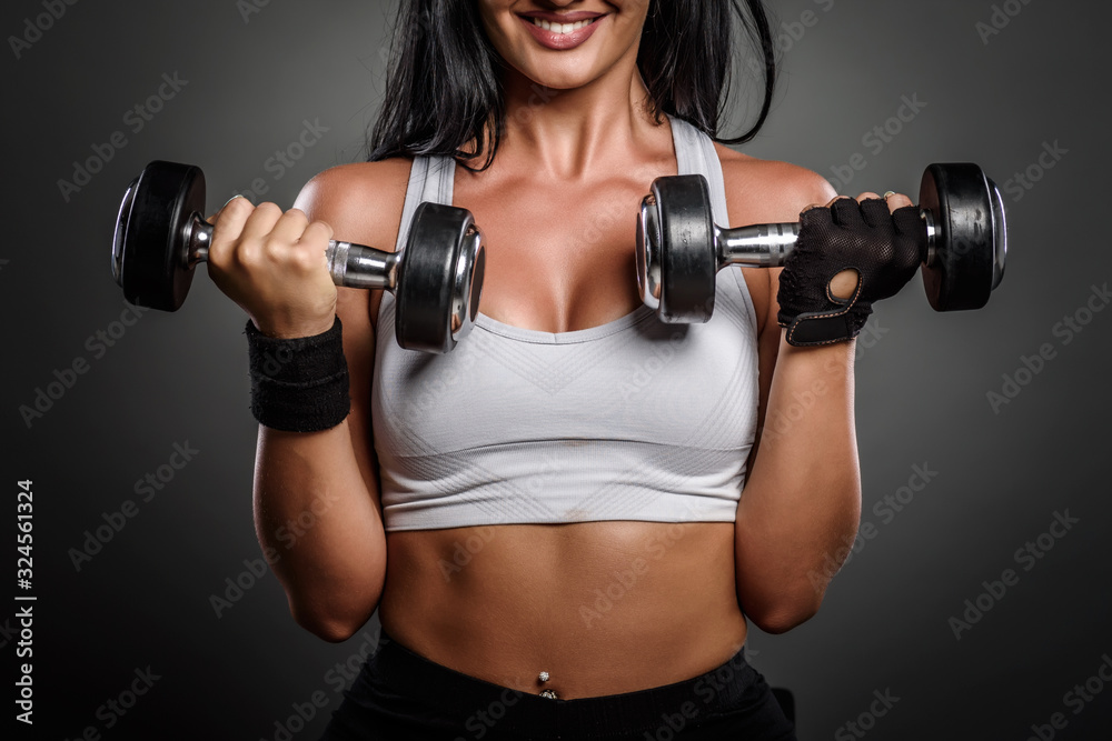 Beautiful young fitness instructor woman posing in studio with weights. Close up detail Beautiful young fitness instructor woman posing in studio with weights. Close up detail