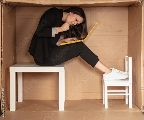 beautiful, angry businesswoman sitting on a desk in a cramped paper office,