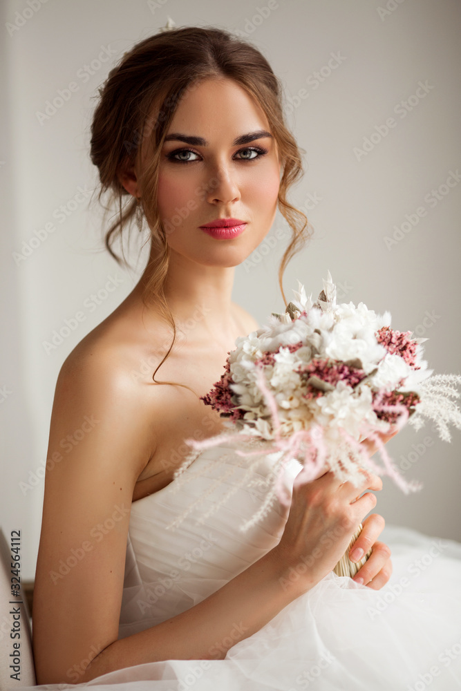 Close up portrait of young bride in a beautiful dress holding a bouquet of flowers in bright white studio. Wedding concept. Close up portrait of young bride in a beautiful dress holding a bouquet of flowers in bright white studio. Wedding concept.