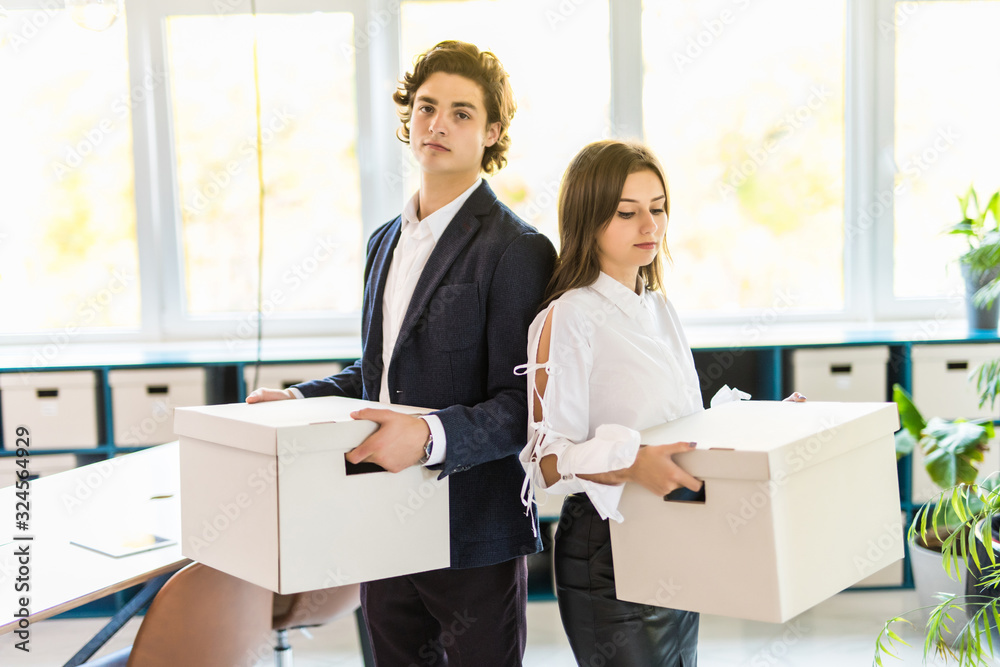 Young happy businessman and a business woman with boxes for moving into a new office Young happy businessman and a business woman with boxes for moving into a new office