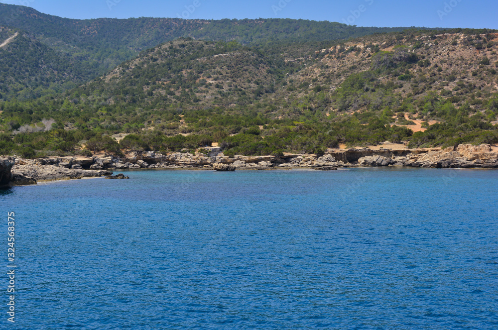 rocky hills covered with greenery into the blue sea