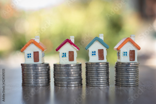  Saving money concept, coin stack growing business, save money for investment. coins to buy a home concept concept for property ladder. A small house on a pile of coins And have a financial chart.