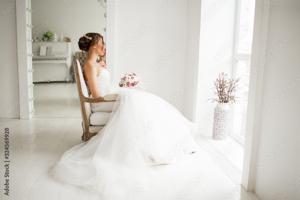 Young bride in a luxury dress holding a bouquet of flowers in bright white studio. Wedding fashion concept. Young bride in a luxury dress holding a bouquet of flowers in bright white studio. Wedding fashion concept.