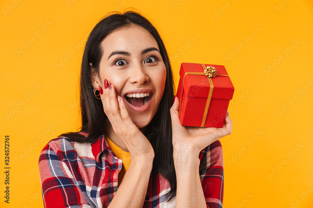 Photo of delighted young woman expressing surprise and holding gift box Photo of delighted young woman expressing surprise and holding gift box