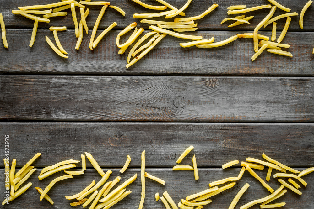 French fries frame on dark wooden background top-down copy space
