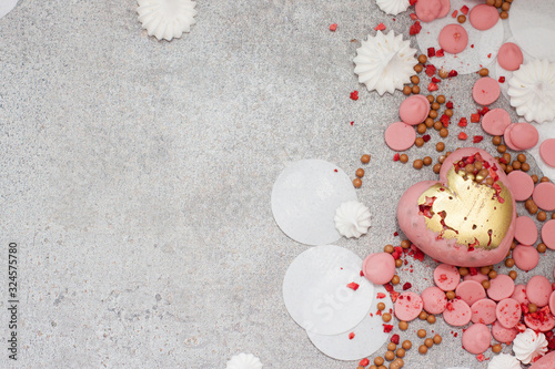 Pink hearts from tempered chocolate with chocolate drops, meringues and dried berries on grey background photo