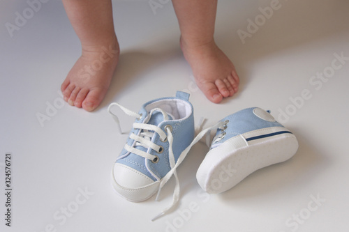 the first baby shoes on the background of the babies feet	 photo
