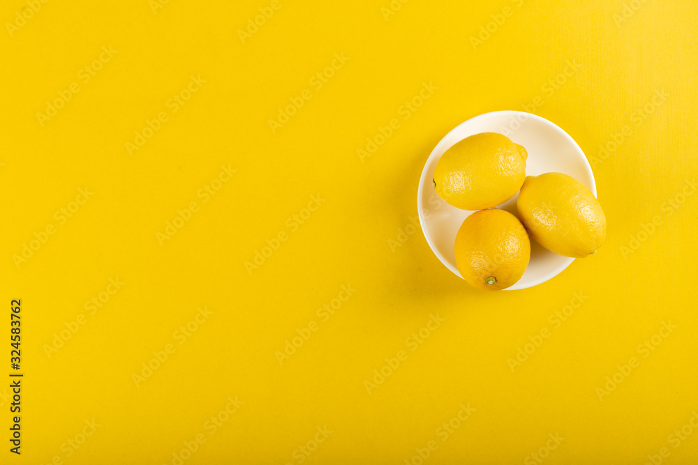 Lemons in a white saucer on yellow Lemons in a white saucer on yellow