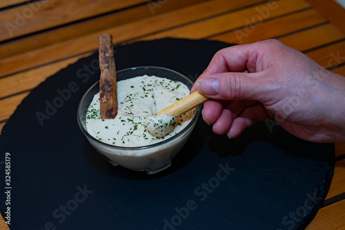 Hand catching hummus with a biscuit.