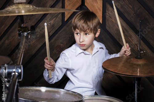 The child plays the drums. Boy musician behind a drum kit.