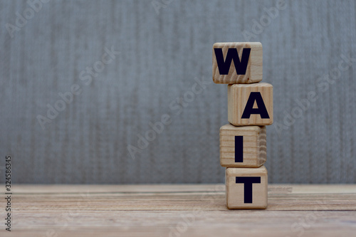 concept word wait on vertical cubes on a gray background