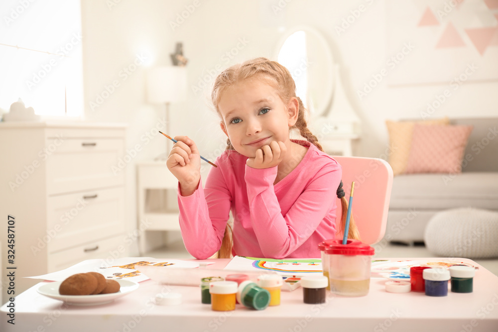 Cute little child painting at table in room Cute little child painting at table in room