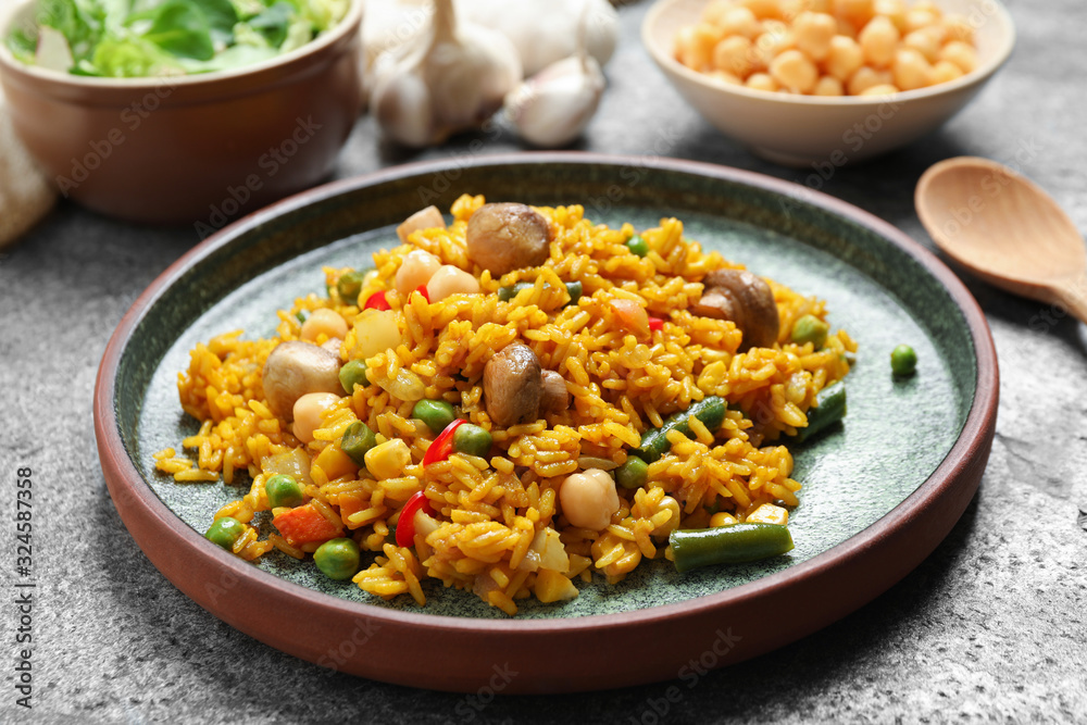Delicious rice pilaf with vegetables on grey table Delicious rice pilaf with vegetables on grey table