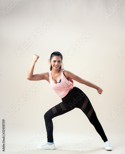 Young lady wearing exercise set twisted her body and face,raise fist up in the air,show basic of dance workout,with happy feeling