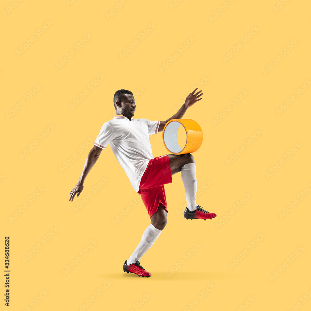 Football player kicking scotch tape on yellow background. Copyspace for your proposal. Modern design. Contemporary artwork, collage. Concept of sport, office, hard work, dreams, business, action.